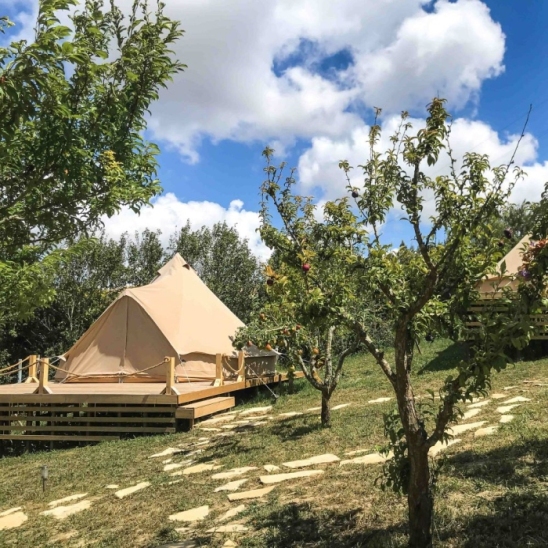 Spring glamping retreat at The Far End Surf House, surrounded by nature and blooming fruit gardens. A stylish tent provides a luxurious camping experience, blending comfort with the serenity of the outdoors.