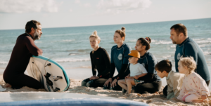 Family on the beach listens surf teacher instructions.