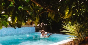 Person relaxing in a pool surrounded by trees.